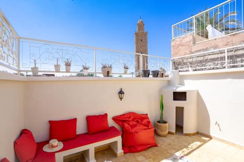 a balcony with red pillows and a red couch at Résidence alqaria assiyahiya in Marrakech