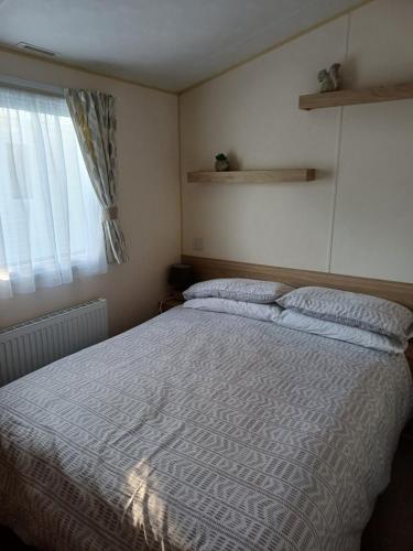 a bedroom with a large bed and a window at Lovely 3 bedroom caravan haven wild duck hoilday Park in Belton