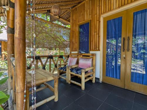 a porch with a swing and a chair on a house at AlBambu in Gili Air