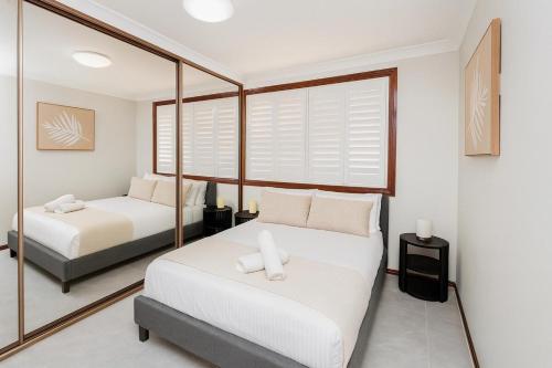 a bedroom with two beds and a mirror at 3 Bedroom Deluxe Family Home in Rooty Hill