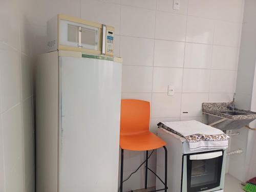 an orange chair sitting next to a refrigerator in a kitchen at Apto central 3104 terreo com ar condicionado in Araçatuba