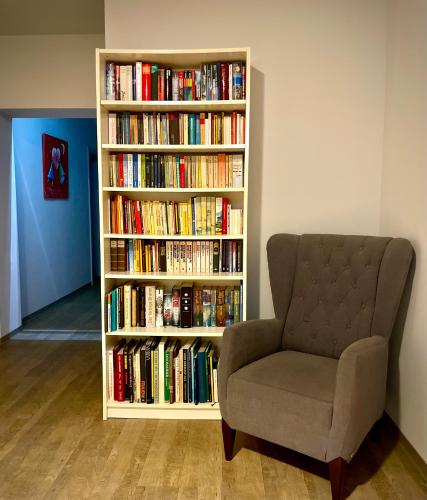 a book shelf filled with books next to a chair at Das SinGold Hotel mit Highspeed WLAN und digitalem Schlüssel in Schwabmünchen