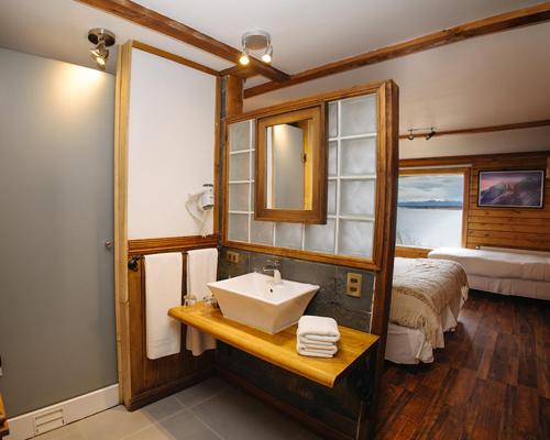a bathroom with a sink and a bed at Weskar Lodge Hotel in Puerto Natales