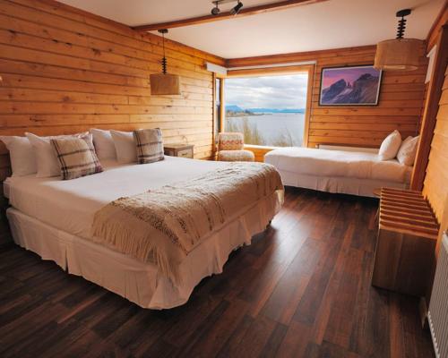 a bedroom with two beds and a large window at Weskar Lodge Hotel in Puerto Natales
