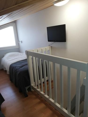 a bedroom with a crib and a flat screen tv at Levin KUURA in Kittilä