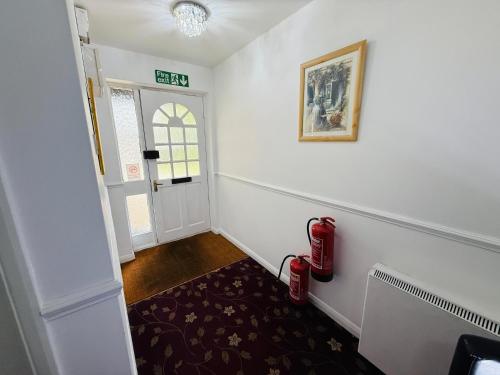 a hallway with a door and a red fire extinguisher at 4 Sisters Inn in North Kyme