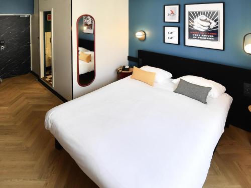 a bedroom with a large white bed and a mirror at ibis Styles Dijon Central in Dijon