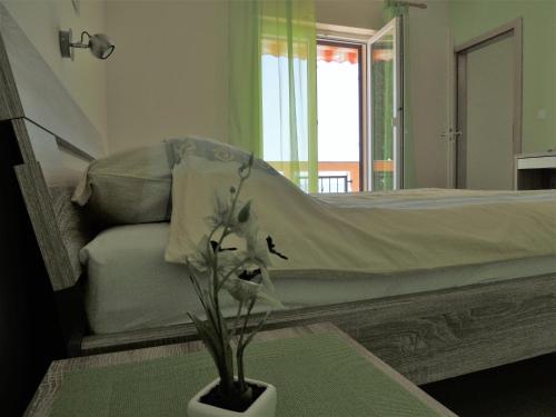ein Schlafzimmer mit einem Bett und einer Vase mit Blumen auf dem Tisch in der Unterkunft Apartments Denona in Novalja