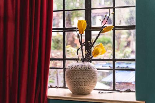 a vase with yellow flowers sitting on a window sill at 柃居 B&B - Jing'an Temple Branch in Shanghai