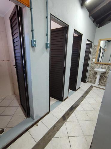 a row of doors in a bathroom with a sink at Hostel de Niko Bombinhas in Bombinhas