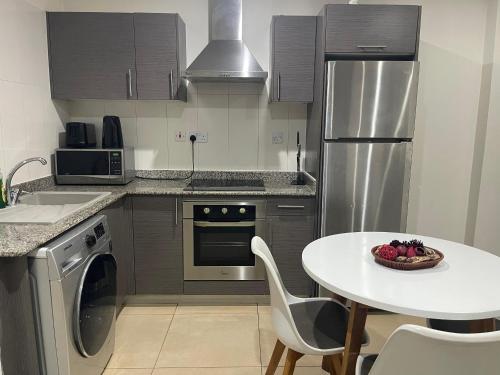 une cuisine avec une table blanche et une table blanche et une assiette de fruits dans l'établissement Kings Luxury 1 bedroom at Gallery, à Accra