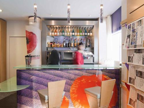 a restaurant with a counter with chairs and a drink at ibis Metz Centre Gare in Metz