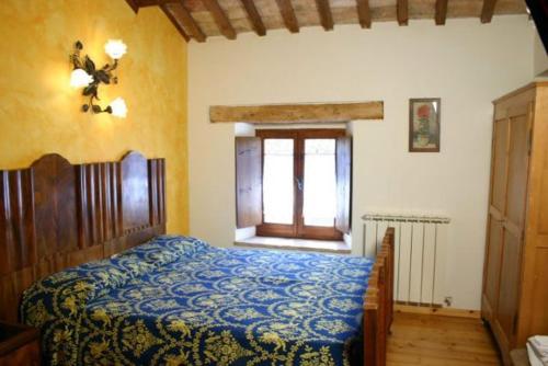 a bedroom with a bed with a blue blanket and a window at Bed and Breakfast San Firmano in Montelupone