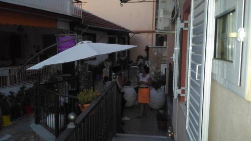 a woman standing under a white umbrella on a balcony at Paraskevi's Luxury Studios in Parga