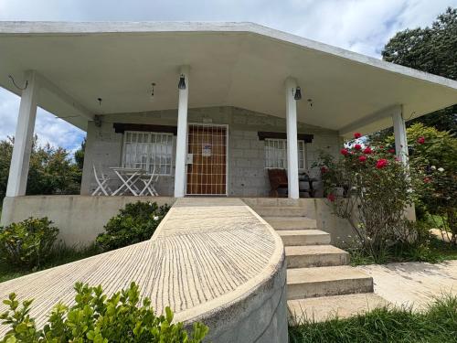 a house with a porch with stairs and flowers at Domo Los Ángeles in Huauchinango