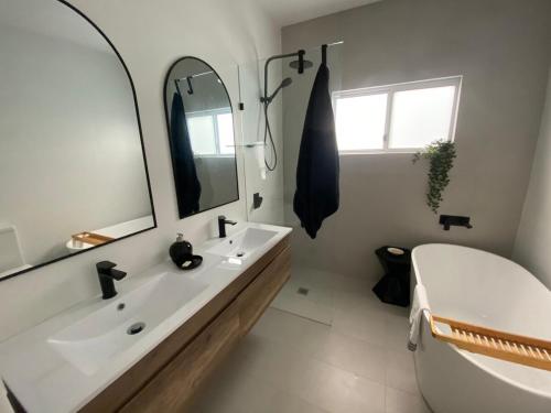 a bathroom with a white tub and a sink and a mirror at Tranquility by the Lake in Karraganbah