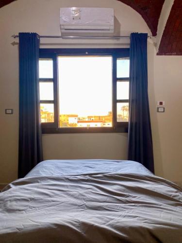 a bedroom with a bed and a window with blue curtains at Tasneem Palace in Luxor