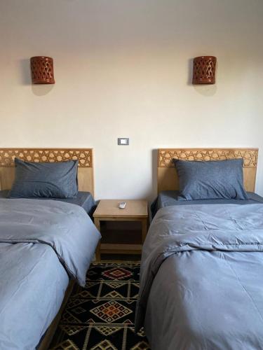 a bedroom with two beds and a table with a night stand at Tasneem Palace in Luxor
