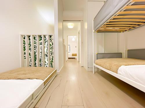 due letti in una stanza con pareti bianche e pavimenti in legno di Entire 2 Bedroom Family Friendly House in Belem Lisbon 3 to 5 Guests a Lisbona