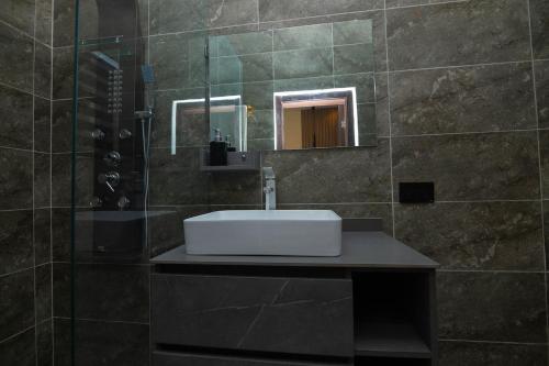 a bathroom with a sink and a shower with a mirror at Bigchills Bills apt in Apenkwa