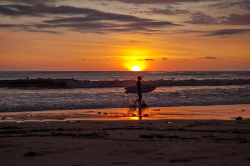 a person walking on the beach with a surfboard at Incredible Views - Brand-New 3BR Condo in Jacó