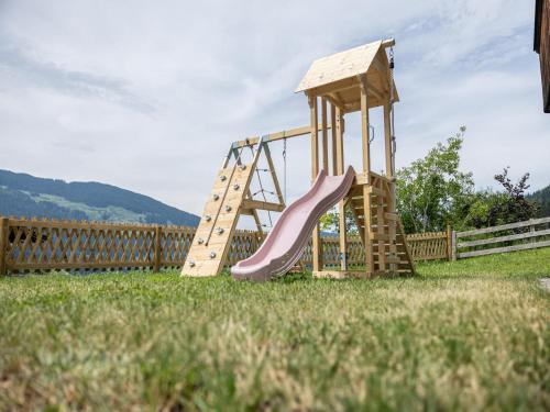 a wooden playground with a slide in a yard at Tirola Chalet Alpbach in Alpbach