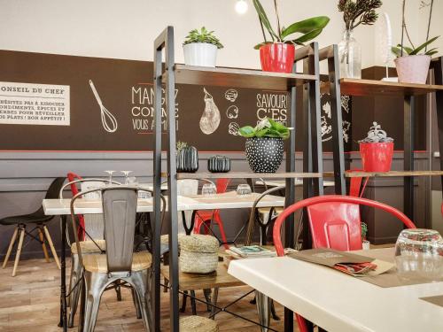a dining room with tables and chairs and plants at ibis Angers Centre Chateau in Angers