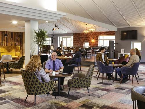 a group of people sitting at tables in a restaurant at Novotel Manchester West in Worsley
