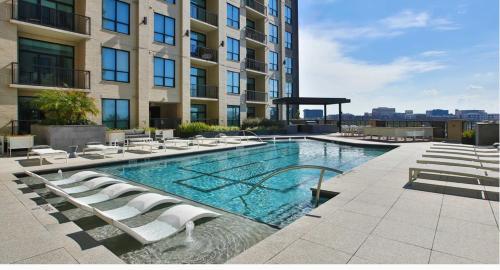 a swimming pool with lounge chairs and a building at Haus of Blues-HighRise-NRG Stadium-Med Center- Private Parking in Houston