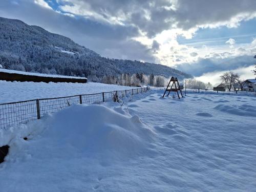 a snow covered field with a fence and a snow mound at Jukbichl 1 in Laas