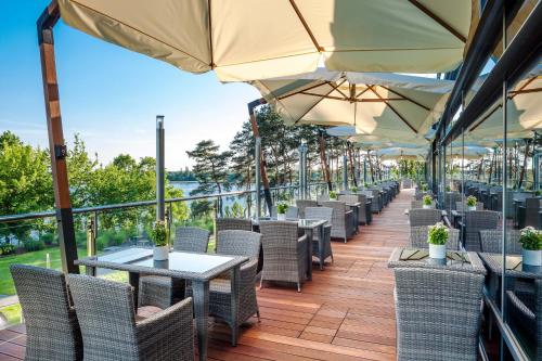 a row of tables and chairs with umbrellas on a deck at Hotel Warszawianka in Jachranka