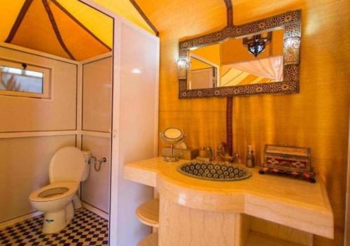 a bathroom with a toilet and a sink with a mirror at Berber Luxurious Camp in Merzouga