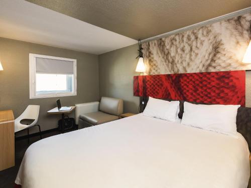 a hotel room with a large bed and a chair at ibis Bordeaux Centre Meriadeck in Bordeaux