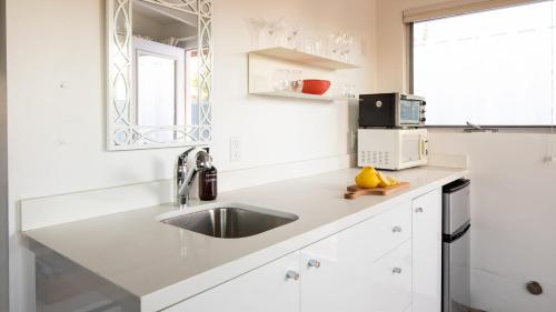 a white kitchen with a sink and a microwave at 3 Private 1 Bedroom Units at The Wesley Sleeps 12 in Palm Springs