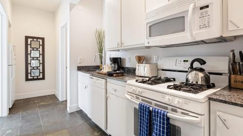 a white kitchen with a stove and microwave at The Cayucan Bungalows by AvantStay Pet-Friendly Getaway Steps from Cayucos State Beach in Cayucos