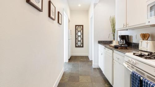 a kitchen with white cabinets and a tile floor at The Cayucan Bungalows by AvantStay Pet-Friendly Getaway Steps from Cayucos State Beach in Cayucos
