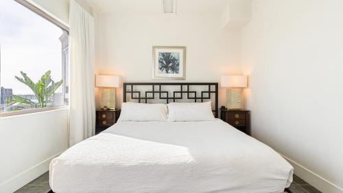 a white bedroom with a bed and two lamps at The Cayucan Bungalows by AvantStay Pet-Friendly Getaway Steps from Cayucos State Beach in Cayucos