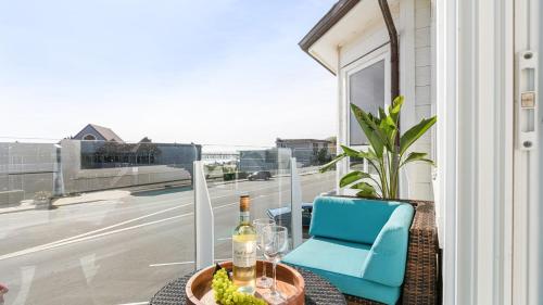 a table with a bottle of wine and a chair on a balcony at The Cayucan Bungalows by AvantStay Pet-Friendly Getaway Steps from Cayucos State Beach in Cayucos