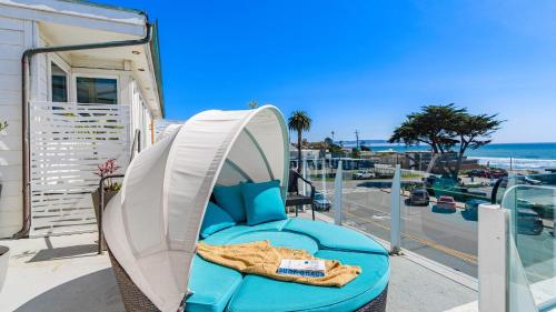 a blue chair on a balcony next to the beach at The Cayucan Bungalows by AvantStay Pet-Friendly Getaway Steps from Cayucos State Beach in Cayucos