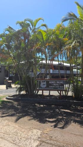 a sign in front of palm trees and a train at Agnes Palms Motel in Agnes Water