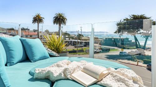 a blue couch with a book on top of it at The Cayucan Bungalows by AvantStay Pet-Friendly Getaway Steps from Cayucos State Beach in Cayucos