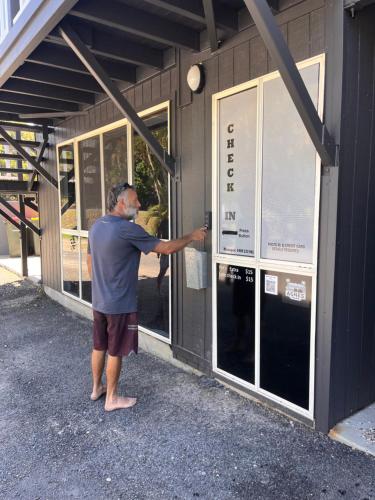 a man is opening a window on a building at Agnes Palms Motel in Agnes Water