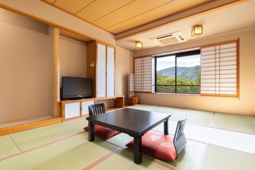 a living room with a table and a tv at KAMENOI HOTEL Tazawako in Senboku