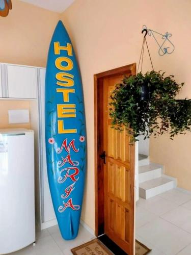 a blue surfboard leaning against a wall next to a door at Hostel Maria in Ubatuba