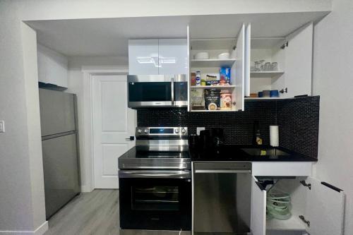 a kitchen with a stove and a microwave at Cozy 2BR Retreat - 10 Mins to WEM - Free Parking & WiFi in Edmonton