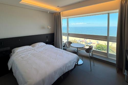 a bedroom with a bed and a view of the beach at 코브스테이 해운대 in Busan