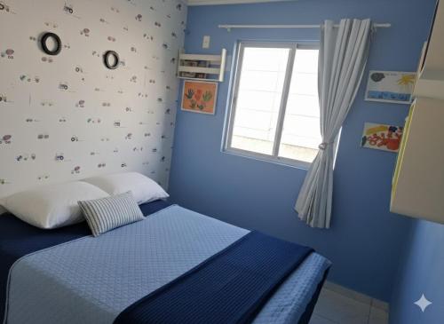 a blue bedroom with a bed and a window at Porto dos Açores in Laguna