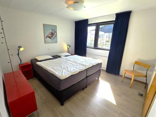 Un dormitorio con una cama y una silla y una ventana. en Holiday home in Oostkapelle with Wi-Fi, en Oostkapelle