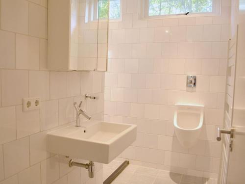 a white bathroom with a sink and a urinal at with large, fenced garden DL108 in Domburg