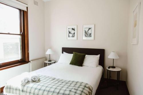 a bedroom with a bed and two lamps and a window at Dormie House in Moss Vale